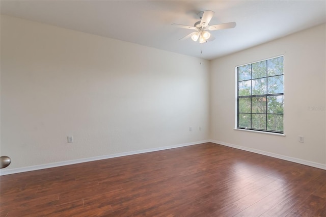 unfurnished room featuring dark wood finished floors, ceiling fan, and baseboards
