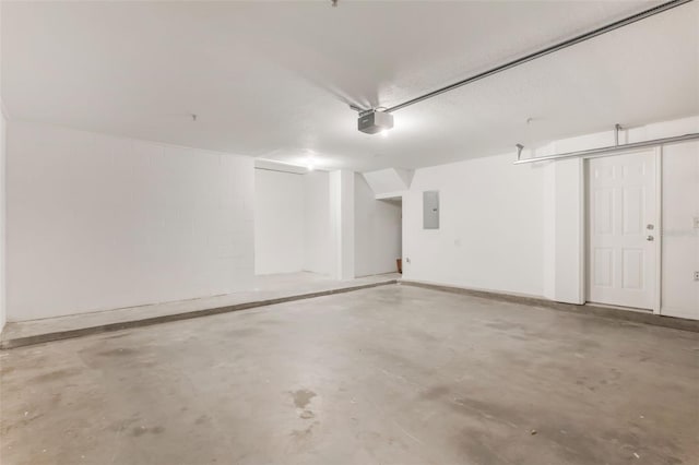 garage featuring a garage door opener, electric panel, and concrete block wall