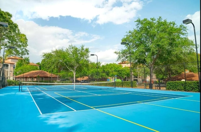 view of tennis court featuring fence and community basketball court
