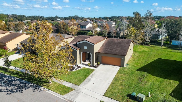 view of front of property with a residential view, an attached garage, a front lawn, and stucco siding