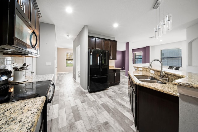 kitchen featuring black appliances, a sink, hanging light fixtures, light wood finished floors, and dark brown cabinets