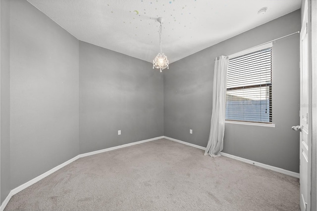 unfurnished room featuring carpet flooring, baseboards, and a chandelier