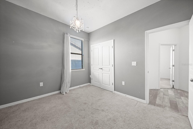 unfurnished bedroom featuring a chandelier, carpet, baseboards, and a closet