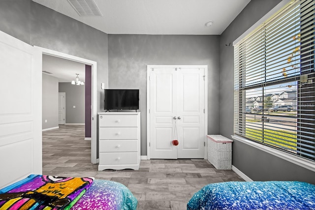 bedroom featuring wood finished floors, multiple windows, a chandelier, and baseboards