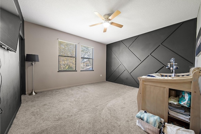 office with ceiling fan, carpet floors, baseboards, a textured ceiling, and an accent wall
