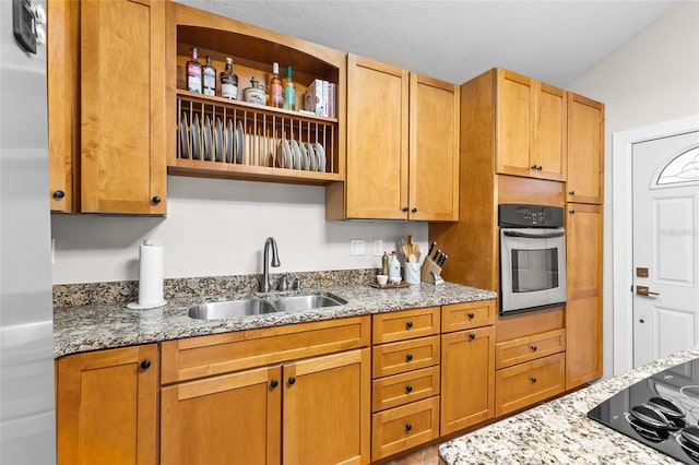 kitchen featuring stainless steel oven, a sink, black electric cooktop, open shelves, and light stone countertops