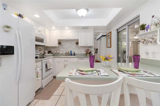 1804 W Shores Rd, Melbourne, FL 32935 - kitchen with white appliances, white cabinetry, light countertops, a raised ceiling, and a sink