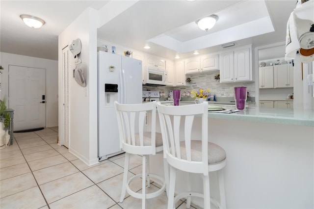 1804 W Shores Rd, Melbourne, FL 32935 - kitchen with white appliances, a raised ceiling, light tile patterned flooring, white cabinets, and a kitchen breakfast bar