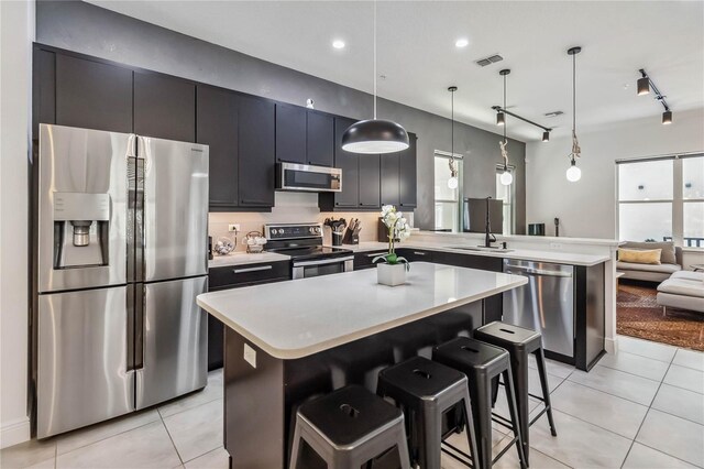 8160 Iron Mountain Trl, Windermere, FL 34786 - kitchen featuring stainless steel appliances, a peninsula, light tile patterned floors, light countertops, and a kitchen breakfast bar