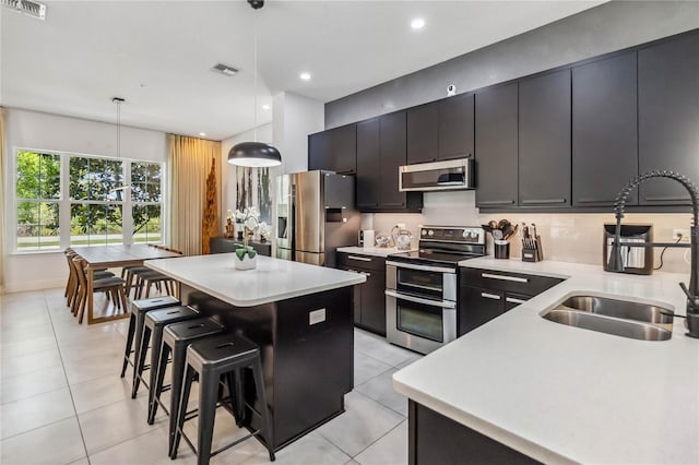 8160 Iron Mountain Trl, Windermere, FL 34786 - kitchen with appliances with stainless steel finishes, a sink, a kitchen island, a breakfast bar, and light countertops