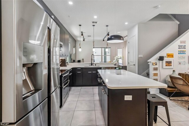 8160 Iron Mountain Trl, Windermere, FL 34786 - kitchen featuring stainless steel appliances, a sink, light tile patterned floors, a breakfast bar, and light countertops