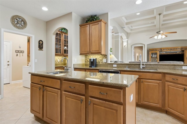724 Duff Dr, Winter Garden, FL 34787 - kitchen with a sink, a center island with sink, light stone countertops, decorative backsplash, and coffered ceiling