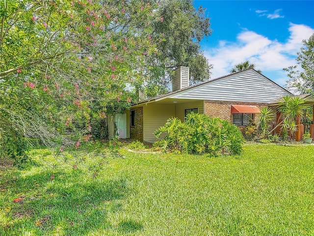 1591 Revere Ln, Daytona Beach, FL 32117 - view of side of home with a chimney, a yard, and brick siding