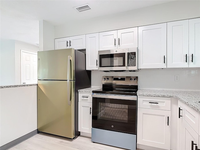 1591 Revere Ln, Daytona Beach, FL 32117 - kitchen with appliances with stainless steel finishes, white cabinets, light wood-type flooring, and light stone countertops