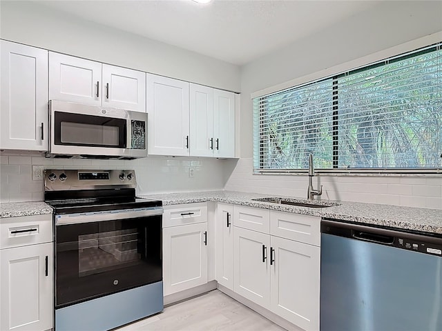 1591 Revere Ln, Daytona Beach, FL 32117 - kitchen with stainless steel appliances, a sink, tasteful backsplash, white cabinets, and light stone countertops