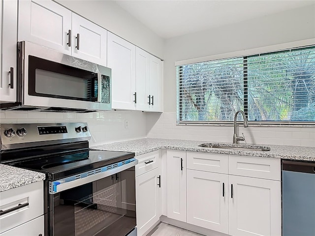 1591 Revere Ln, Daytona Beach, FL 32117 - kitchen with appliances with stainless steel finishes, a sink, backsplash, white cabinets, and light stone countertops
