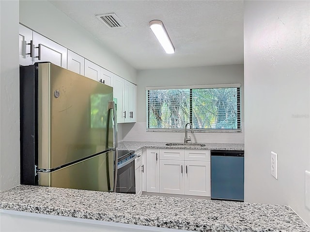 1591 Revere Ln, Daytona Beach, FL 32117 - kitchen featuring freestanding refrigerator, dishwashing machine, a sink, white cabinets, and light stone countertops