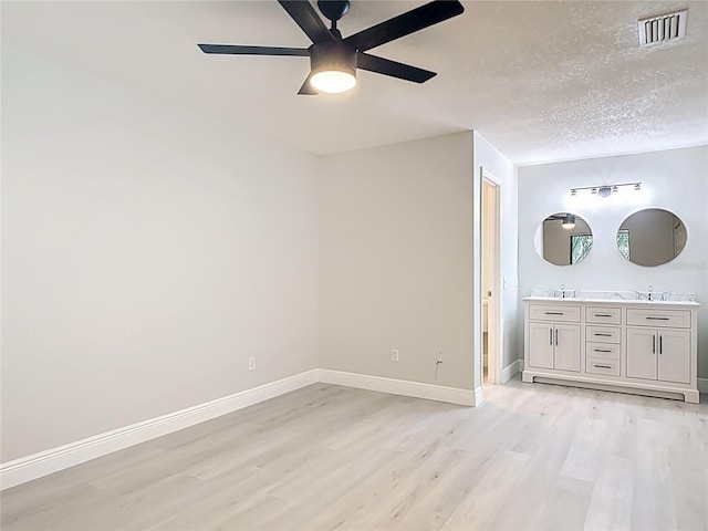 1591 Revere Ln, Daytona Beach, FL 32117 - unfurnished bedroom featuring light wood-style floors, baseboards, a sink, a ceiling fan, and a textured ceiling