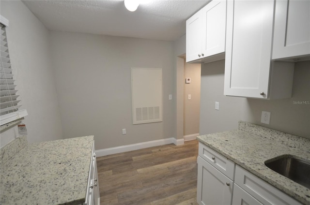 1238 Conley St, Orlando, FL 32805 - kitchen with wood finished floors, white cabinets, light stone countertops, and baseboards