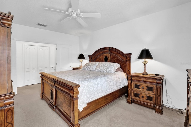 bedroom with light colored carpet, a closet, and a ceiling fan