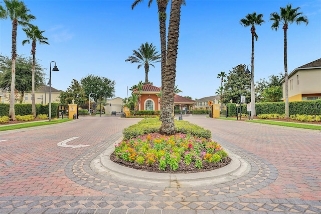 view of decorative road with a gate, street lighting, and curbs