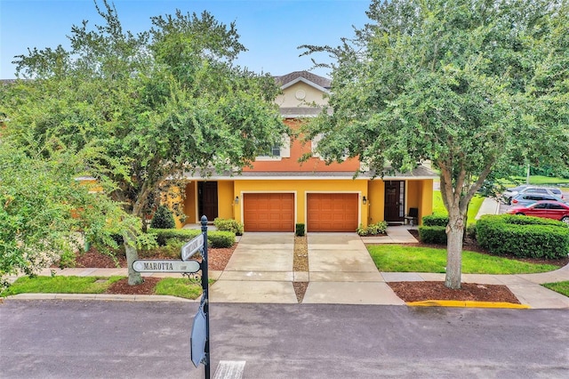 view of front facade with stucco siding, driveway, and a garage