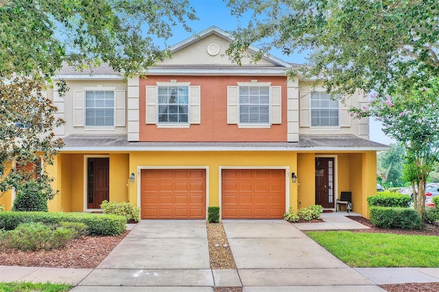 multi unit property featuring stucco siding, driveway, an attached garage, and roof with shingles