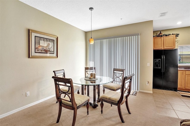 dining room featuring baseboards, light carpet, and a textured ceiling