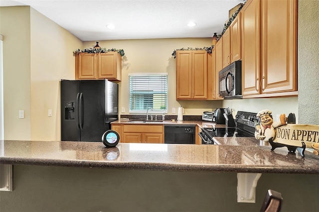 kitchen with black appliances, a sink, dark stone counters, a peninsula, and recessed lighting