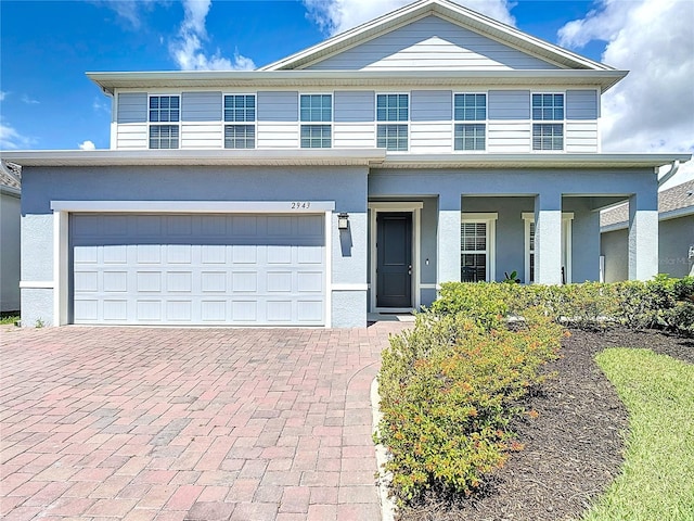 2943 Slough Creek Dr, Kissimmee, FL 34744 - view of front of home featuring decorative driveway, a garage, and stucco siding