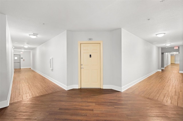 hall featuring baseboards and wood finished floors