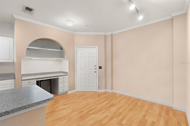 interior space with light wood-type flooring, ornamental molding, and baseboards