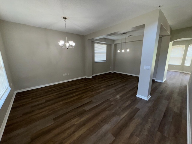3707 Andover Cay Blvd, Orlando, FL 32825 - unfurnished dining area featuring a chandelier, dark wood finished floors, baseboards, and arched walkways