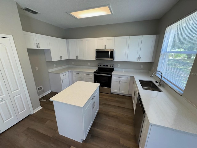 3707 Andover Cay Blvd, Orlando, FL 32825 - kitchen with a sink, appliances with stainless steel finishes, a center island, dark wood-style flooring, and white cabinetry