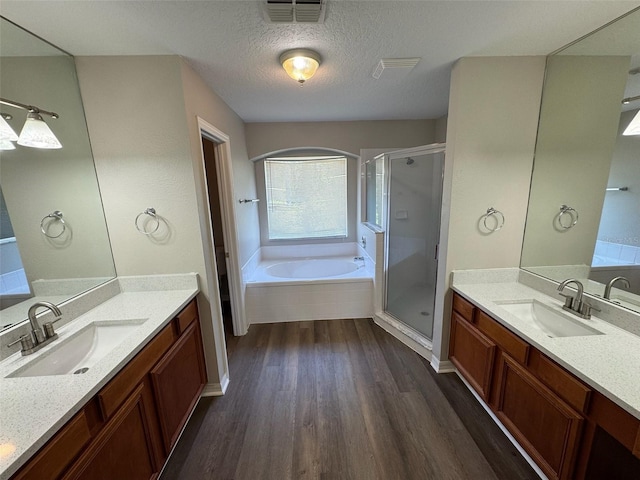 3707 Andover Cay Blvd, Orlando, FL 32825 - bathroom with wood finished floors, a stall shower, a bath, two vanities, and a textured ceiling