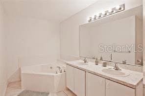 bathroom with a garden tub, double vanity, and tile patterned flooring