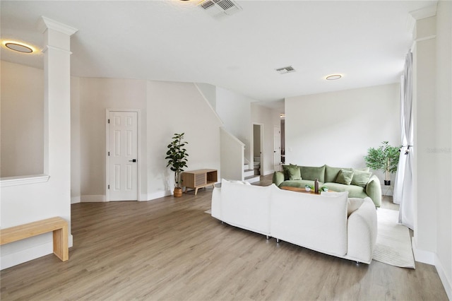 7551 Bear Claw Run, Orlando, FL 32825 - living room with light wood-style floors, stairs, baseboards, and decorative columns