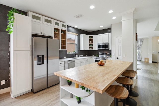 7551 Bear Claw Run, Orlando, FL 32825 - kitchen featuring open shelves, appliances with stainless steel finishes, ornate columns, light wood-type flooring, and white cabinetry