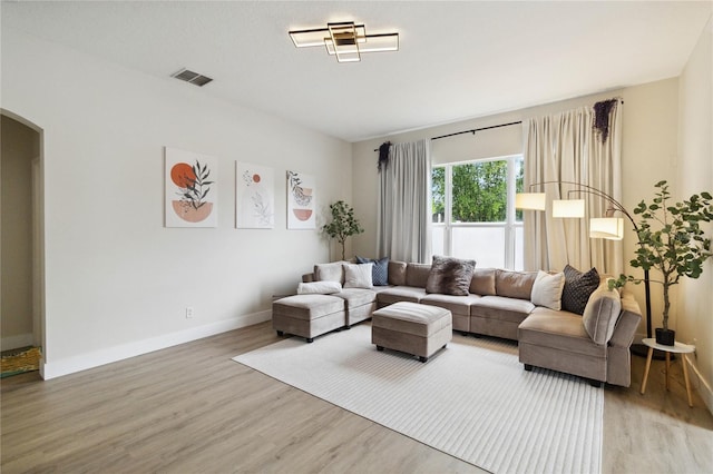 7551 Bear Claw Run, Orlando, FL 32825 - living room featuring arched walkways, light wood finished floors, and baseboards