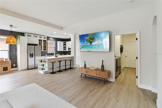7551 Bear Claw Run, Orlando, FL 32825 - living room with light wood-style flooring, baseboards, recessed lighting, ornate columns, and arched walkways