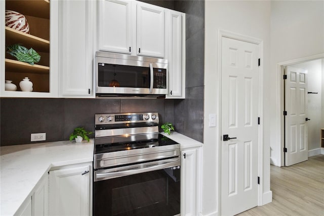7551 Bear Claw Run, Orlando, FL 32825 - kitchen with appliances with stainless steel finishes, white cabinets, light stone counters, and light wood-style floors