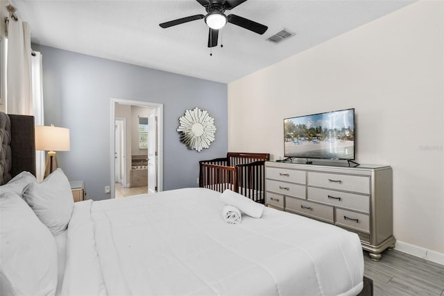 bedroom with baseboards, ensuite bathroom, light wood-type flooring, and a ceiling fan