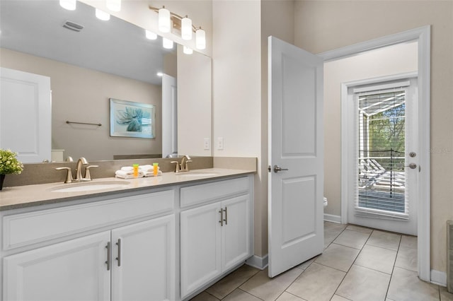 full bathroom with double vanity, tile patterned floors, baseboards, and toilet