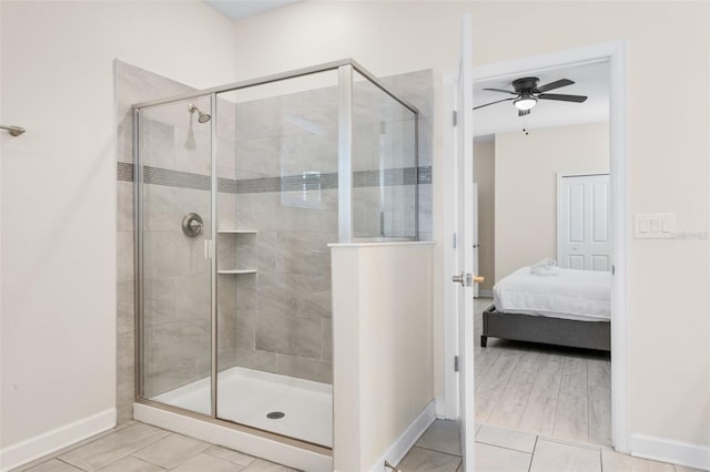 ensuite bathroom featuring ceiling fan, baseboards, a shower stall, and tile patterned floors
