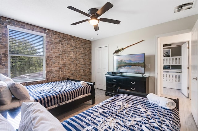 bedroom featuring wood finished floors, brick wall, and ceiling fan