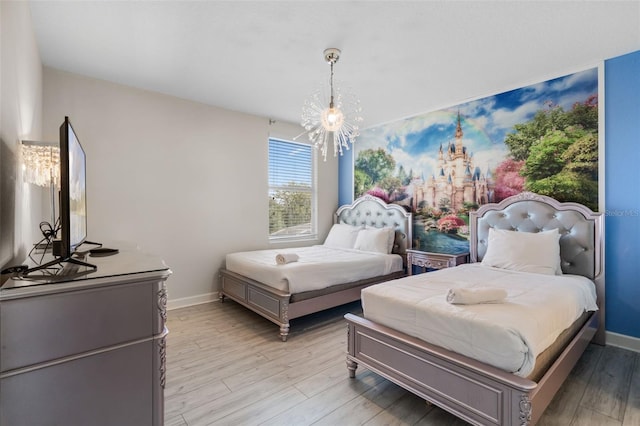 bedroom featuring light wood finished floors, baseboards, and a chandelier