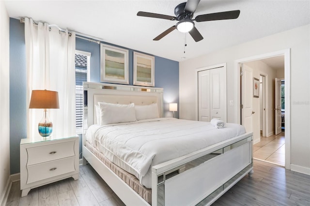 bedroom featuring light wood finished floors, baseboards, a closet, and ceiling fan