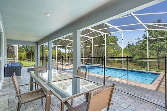 view of swimming pool with a patio area, a pool with connected hot tub, glass enclosure, and outdoor dining space