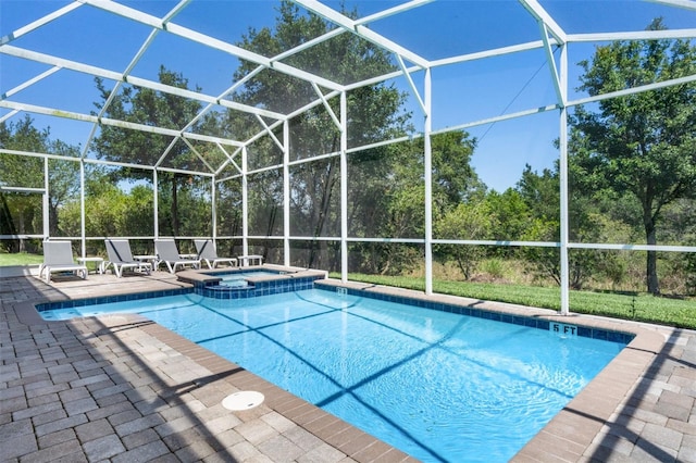 view of swimming pool featuring a pool with connected hot tub, a patio area, a lanai, and view of wooded area