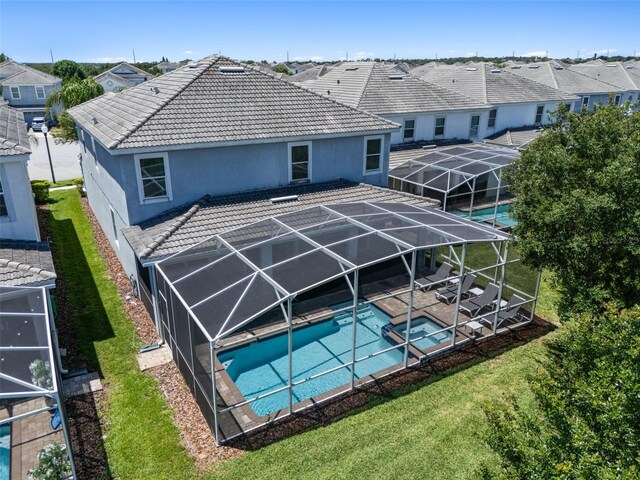back of property featuring a patio area, glass enclosure, a tile roof, a pool with connected hot tub, and a residential view